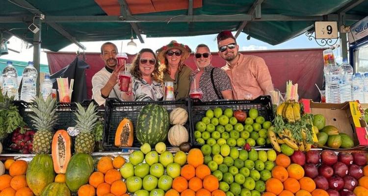Puesto de jugos de frutas vibrante repleto de cítricos y melones con vendedores sonrientes y turistas posando