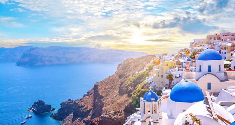 Les dômes bleus emblématiques de Santorin surplombant la mer Égée au coucher du soleil.