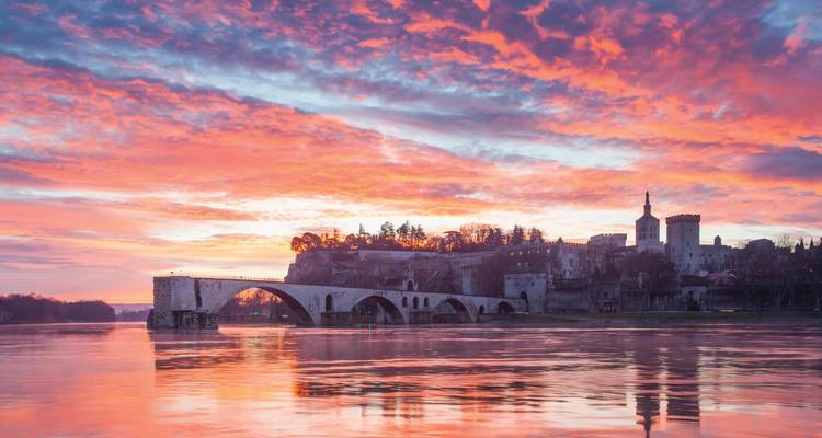 Le Pont Saint-Bénézet d'Avignon et le paysage urbain au coucher du soleil se reflétant sur la rivière.