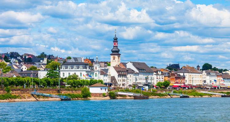 Ville historique au bord de la rivière avec un clocher d'église imposant.