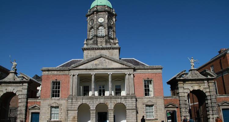 Edificio histórico con una torre de reloj distintiva destacándose contra un cielo despejado.