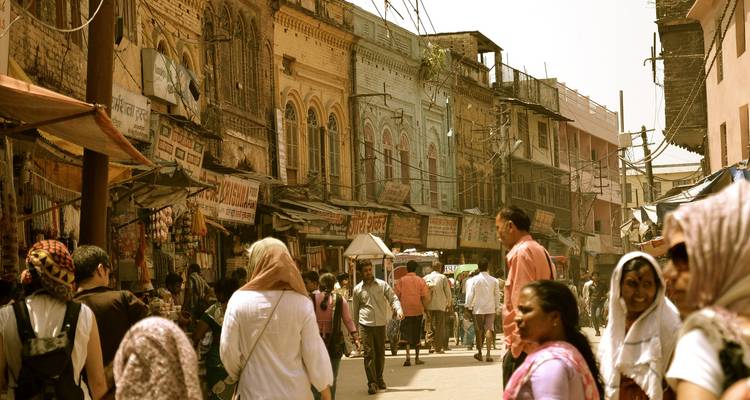 Bustling street with people and shops in a busy market area under sunlight.
