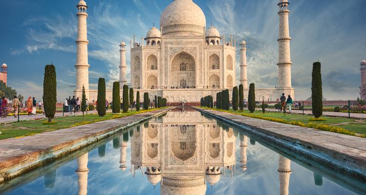 The Taj Mahal with a reflection in the foreground under a clear blue sky.