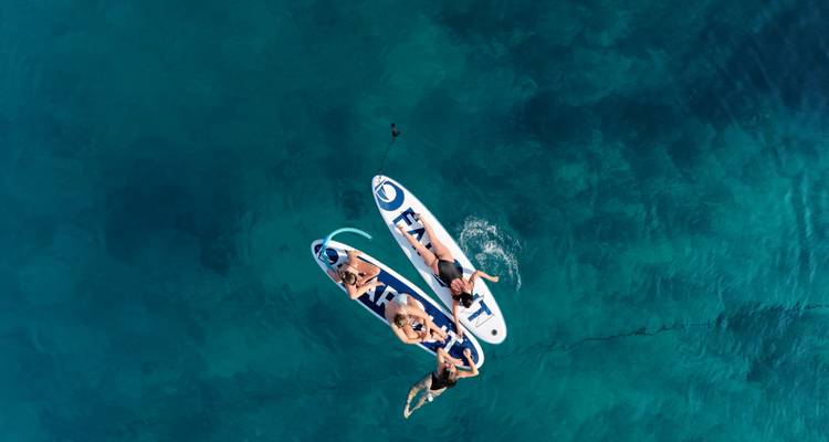 Menschen entspannen auf Paddleboards auf klarem Wasser.