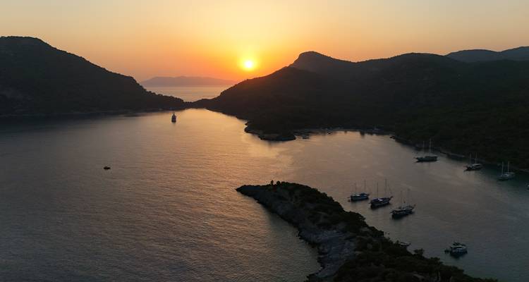Sonnenuntergang über einer schmalen Meerenge mit verstreuten Booten.