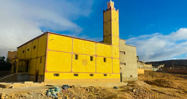 Bâtiment jaune vif avec une tour contre un ciel bleu clair.