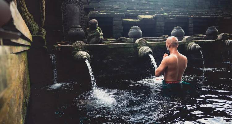 Man performing a ritual in a sacred water temple.
