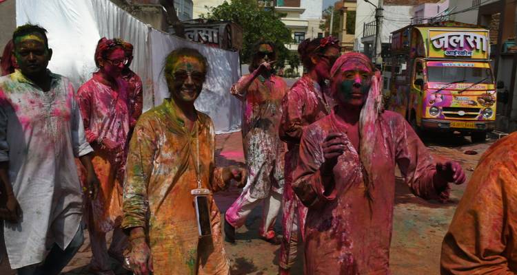 Group of people enjoying the festival of Holi, covered in vibrant colors.