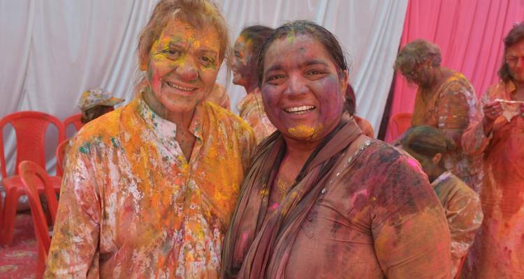 Two people smiling and covered in colors at a Holi celebration.
