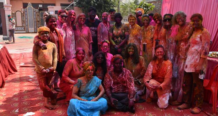 Large group of people posing with colored powders during Holi festival.
