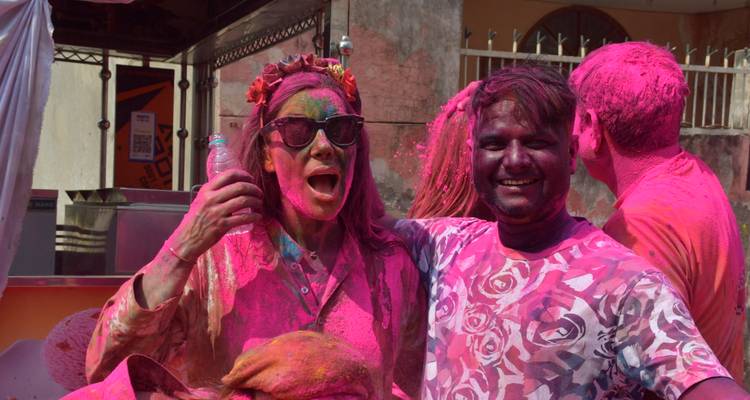 People enjoying Holi festival covered in pink colors.