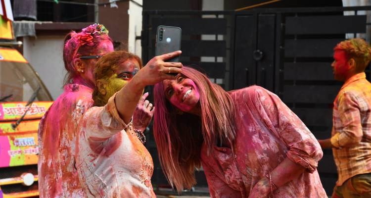Two women taking a selfie covered in Holi colors.