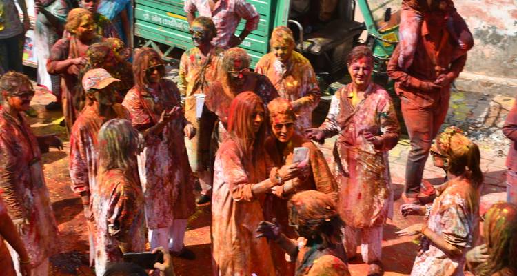 People interacting and enjoying Holi festival with colored powders.