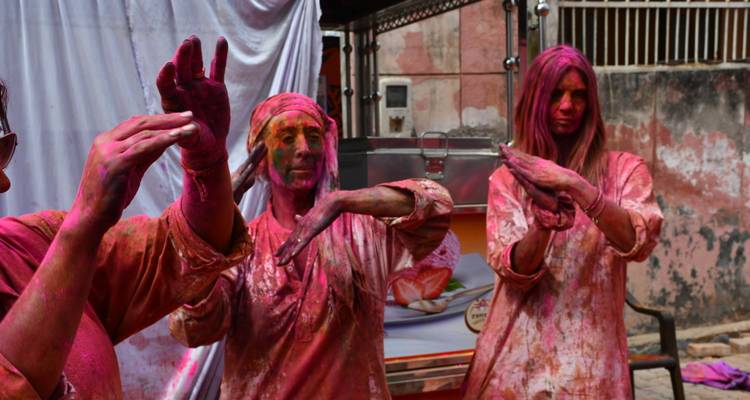 People dancing with colors during Holi celebration.