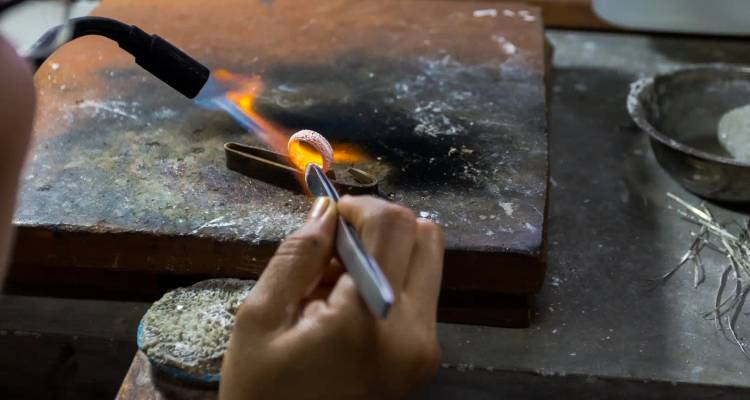 Close-up van een persoon die metaalbewerking uitvoert met een vlammende toorts.