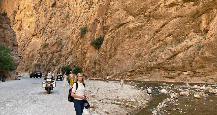 Des personnes marchant dans un paysage rocheux près d'un ruisseau.