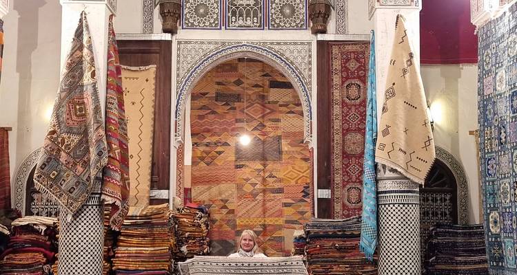 Étalage de marché avec des textiles colorés et une personne derrière un comptoir.