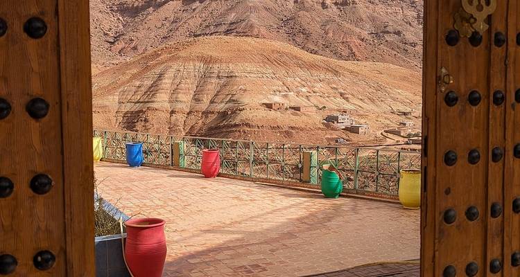 Portes ouvertes encadrant une vue sur la montagne avec des pots colorés.