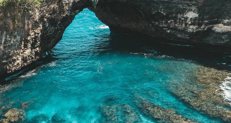 Océan bleu clair sous une arche de roche naturelle.