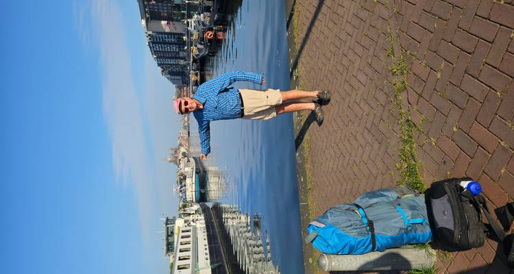Homme pointant du doigt le canal d'eau avec un environnement urbain.