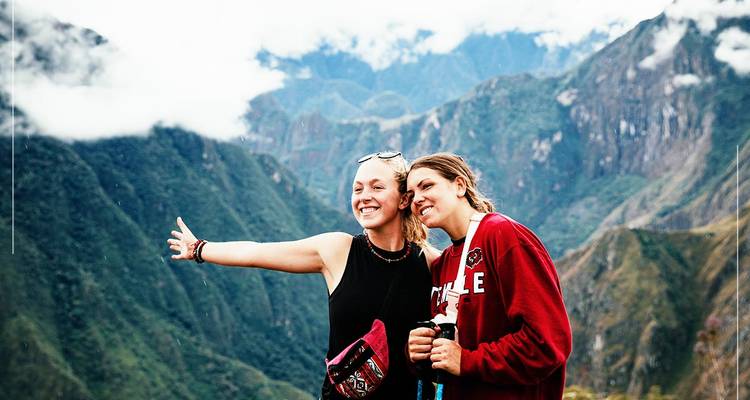 Two women posing with a mountain range in the background.