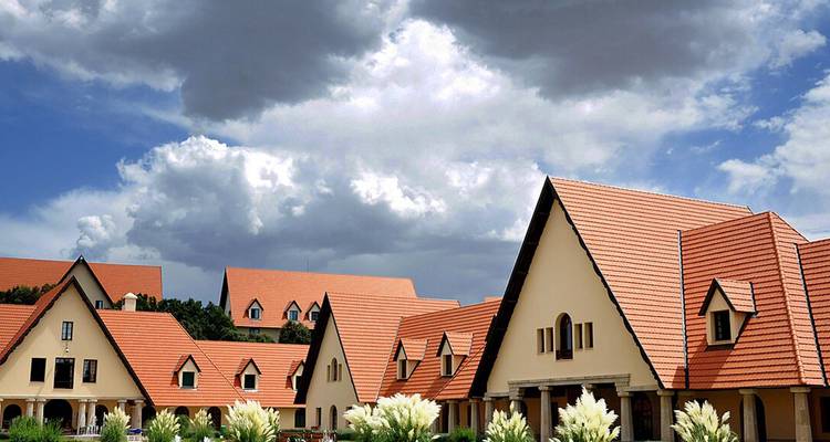 Row of buildings with orange tile roofs under a cloudy sky.