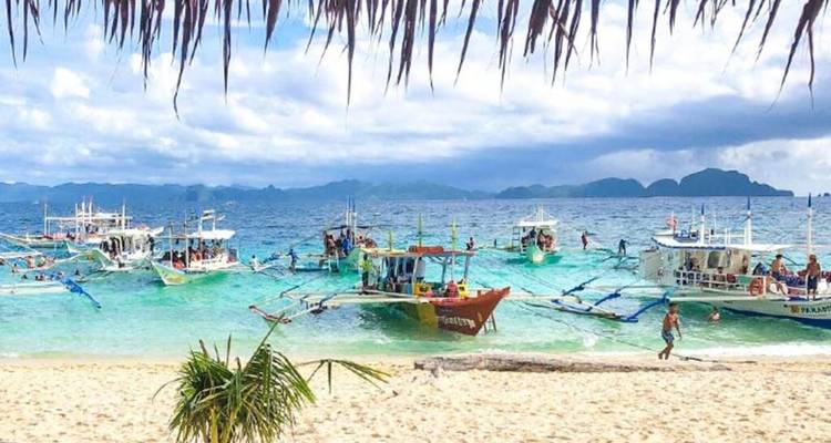 Plage avec bateaux et gens dans l'eau.