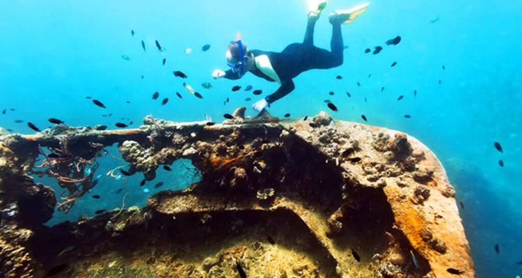Vue sous-marine d'un plongeur explorant une épave de navire.