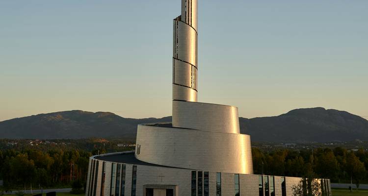 Modern spiral-shaped building with a mountainous backdrop.