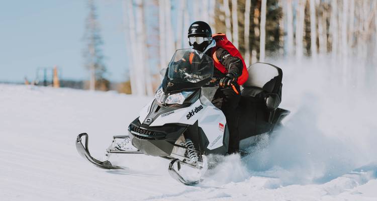 Person riding a snowmobile through snow.