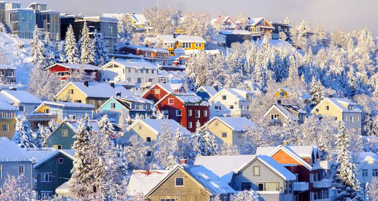 Verschneite Stadt mit bunten Häusern an einem Berghang.