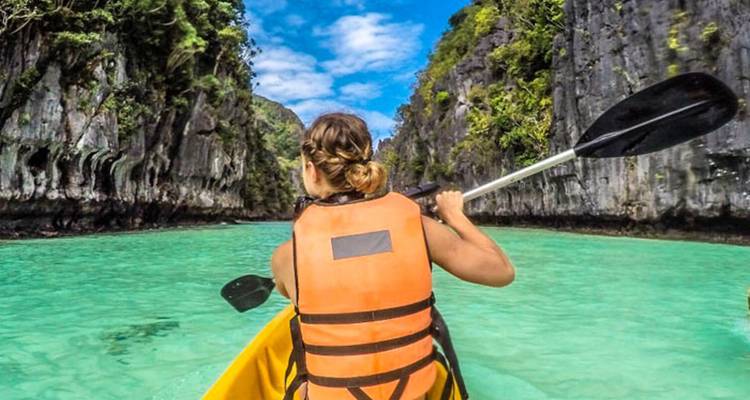 Personne faisant du kayak dans une eau turquoise claire entourée de falaises.