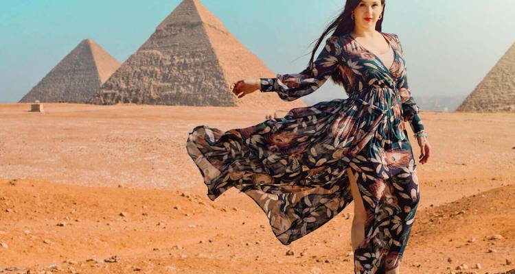 Femme vêtue d'une robe ample posant devant les pyramides emblématiques de Giza sur un plateau désertique