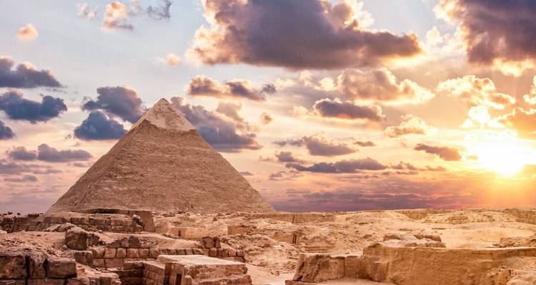Pyramide de Giza brillant sous des nuages de coucher de soleil dramatiques et une lumière dorée.