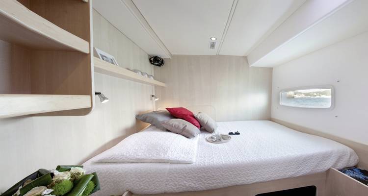 Intérieur d'une chambre de yacht avec grand lit, coussins et décoration.