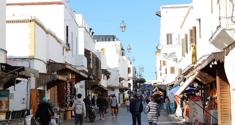 Scène de rue animée avec des gens qui traversent un marché.