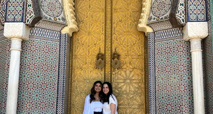 Deux personnes debout devant une grande porte ornée avec des mosaïques colorées