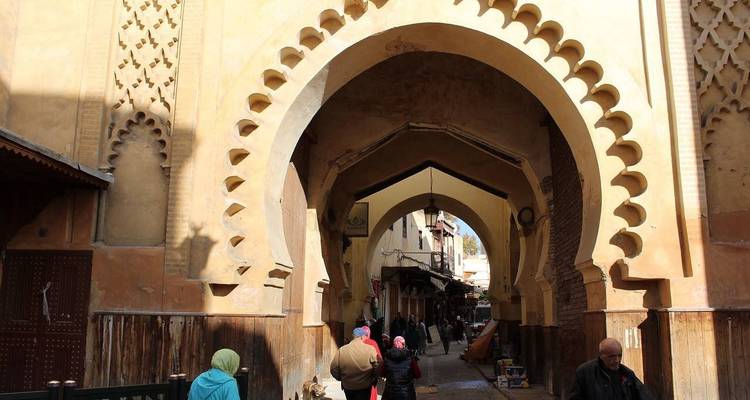 People walking under an arched entrance in a historic city