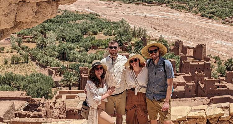 Group of four tourists posing with Ait Benhaddou in the background.