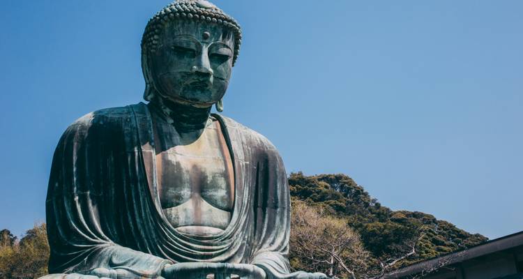 Grande statue de Bouddha en bronze contre un ciel bleu dégagé.
