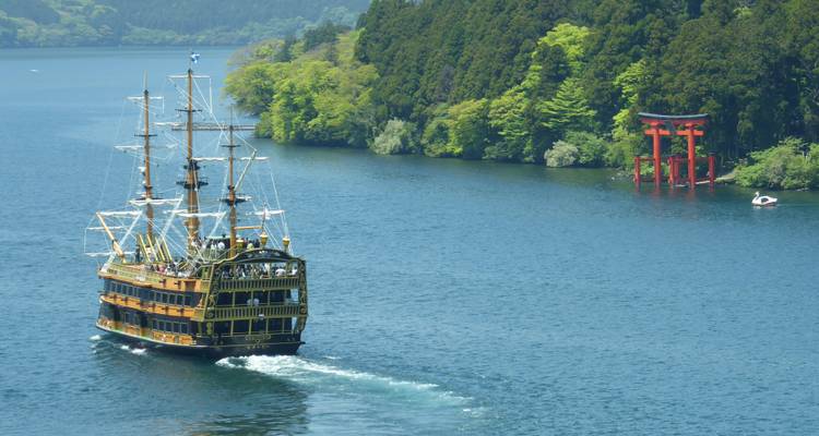 Réplique de bateau pirate naviguant sur un lac avec un torii en arrière-plan.