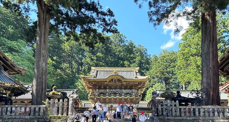 Temple japonais traditionnel entouré d'arbres avec des visiteurs à l'entrée.