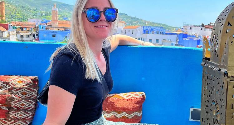 Personne assise sur un toit avec vue sur les bâtiments bleus de la ville.