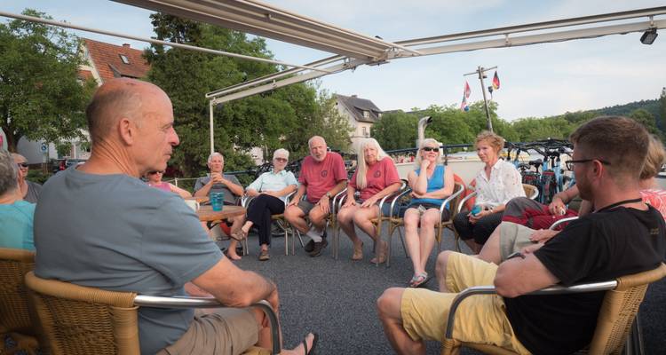 Group of people sitting outdoors in a circle having a casual gathering.