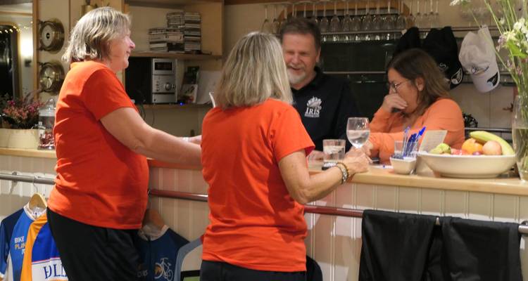 People at a bar counter inside a boat named Iris.