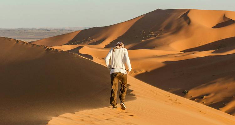 Personne marchant sur le bord d'une dune de sable.