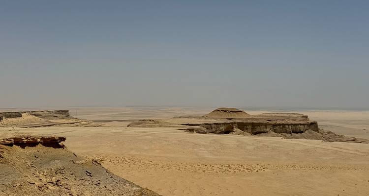 Expansive desert landscape with distant rock formations.