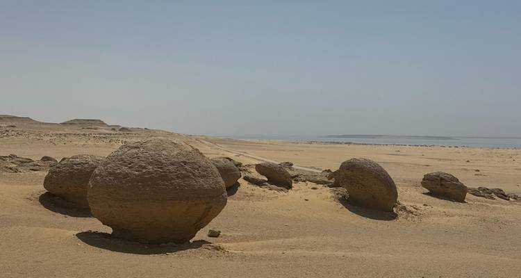 Round rock formations in a sandy desert landscape.