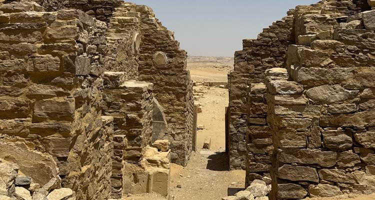 Ruins of stone walls in a desert with open sky.