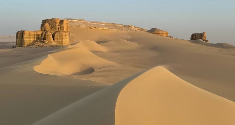 Dunes and rock formations in golden desert light
